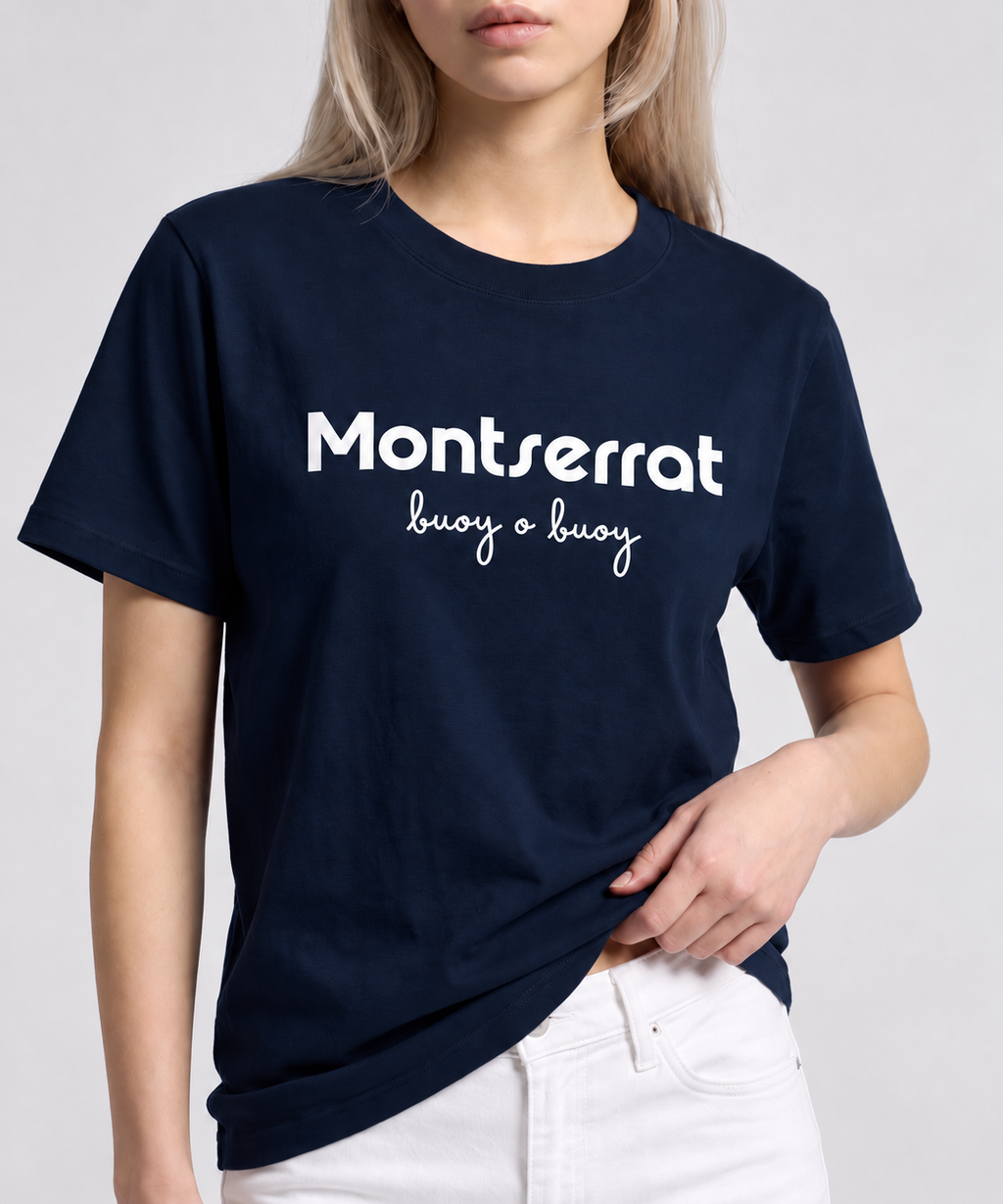 A woman wearing a navy blue Montserrat crewneck t-shirt with 'Montserrat buoy o buoy' printed in white across the chest, paired with white pants, against a white background.