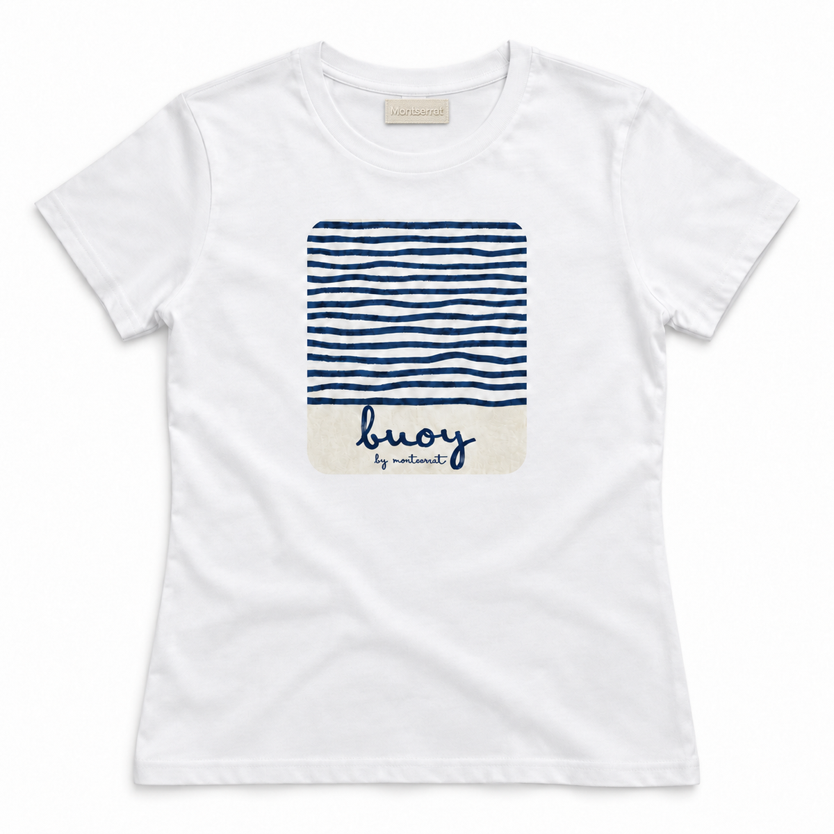 A white short-sleeve crewneck t-shirt by Montserrat, featuring a central graphic print of navy blue horizontal stripes on the top half and a cream-colored bottom half with the brand name 'buoy by Montserrat' written in navy script.