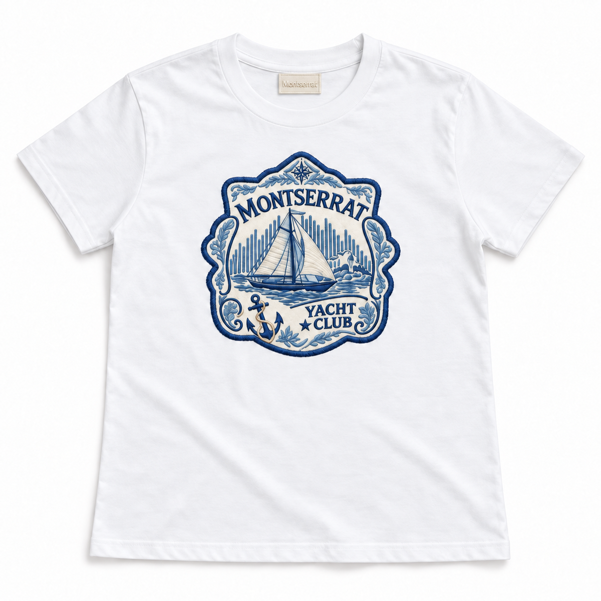 A white short-sleeve crewneck t-shirt featuring a blue and navy graphic print on the front with a sailboat, anchor, and the text 'Montserrat Yacht Club'.